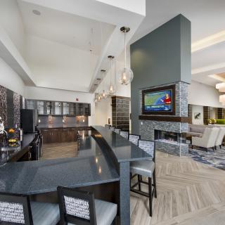 A modern kitchen and bar area with sleek countertops and a wall-mounted television.