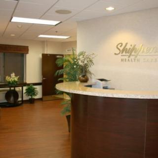 A modern office reception area with a curved desk and decorative plants.