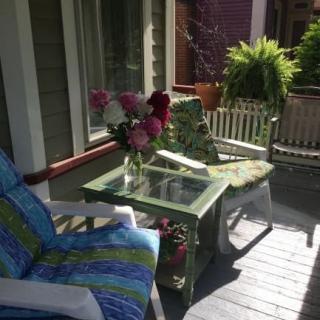 A cozy patio with chairs and a table adorned with flowers, basking in sunlight.