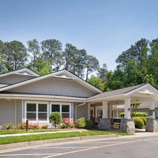 A residential building surrounded by trees and landscaping on a clear day.