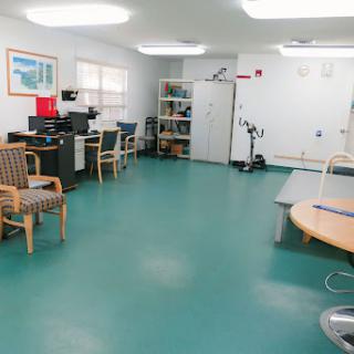 A spacious medical rehabilitation room equipped with exercise equipment and seating areas.