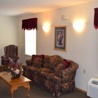 A cozy living room featuring a floral-patterned couch, an armchair, and a wooden coffee table.