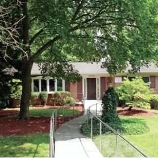 A suburban house with a landscaped front yard and a tree-lined pathway.