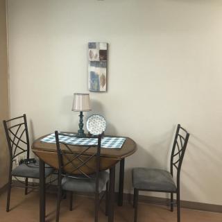 A cozy dining area with a small table and chairs, decorated with a lamp and wall art.