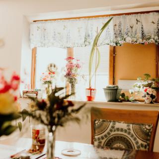 A cozy dining area adorned with colorful flowers and plants, basking in natural light.