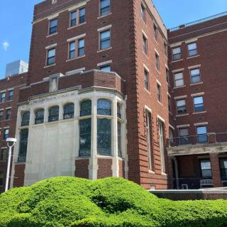 A historical brick building with lush greenery under a clear blue sky.