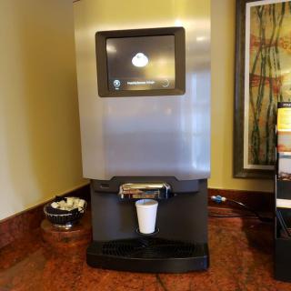 A self-service coffee machine in a hotel lobby ready to dispense a hot beverage.