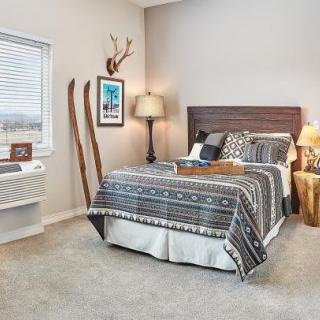 A cozy rustic bedroom featuring a stylish bed with patterned bedding, decorative wall art, and vintage skis as part of the decor.