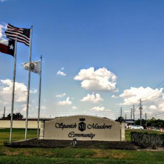 A view of the Apache Junction entrance sign with flags waving under a clear blue sky.