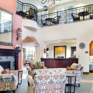 A spacious and elegantly decorated lobby area featuring comfortable seating, a fireplace, and an upper-level balcony.