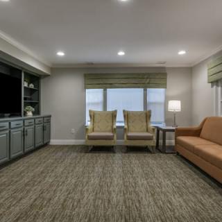 A cozy living room with a sofa, chairs, and a carpeted floor.