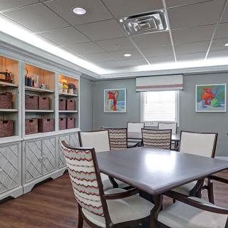 A well-lit conference room with a central table, chairs, and bookshelves lining the walls.