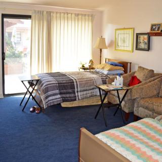 A cozy bedroom with two beds, a sofa, and a small table by the window.