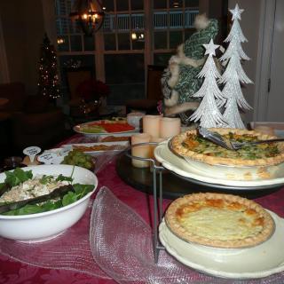 A festive holiday table set with quiches, salad, and Christmas decorations.