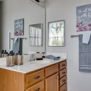 A neatly organized bathroom with a wooden cabinet, decorative wall art, and towels.