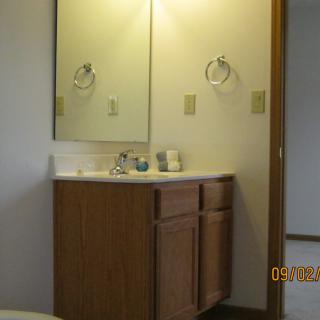 A bathroom with a wooden vanity and mirror above the sink.