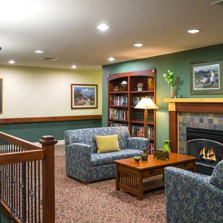 A cozy living room with a fireplace, comfortable seating, and a bookshelf.