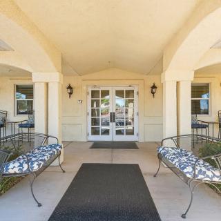 A welcoming building entrance with benches on either side and glass doors.