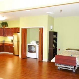 A spacious apartment interior featuring an open kitchen and bedroom area with hardwood flooring.
