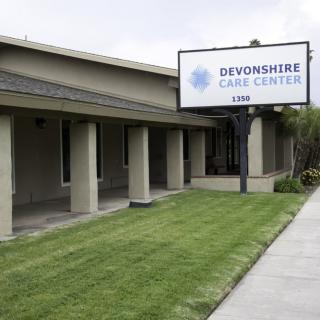 Exterior view of a care center with a visible sign and landscaped lawn.