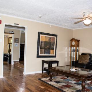 A cozy living room with a ceiling fan, hardwood floors, and stylish decor.