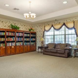 A cozy library corner with bookshelves, a sofa, and large windows.