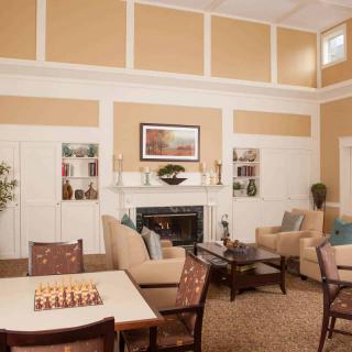 A cozy living room with a fireplace, comfortable seating, and a chessboard on the table.