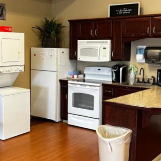A cozy kitchen space featuring modern appliances, including a stacked washer and dryer set, a refrigerator, an oven, a microwave, and a sink.