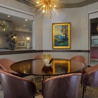 A stylish dining room featuring a round table with leather chairs, modern lighting, and framed artwork on the wall.