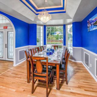 A vibrant dining room with striking blue walls, a chandelier, and a wooden dining set.