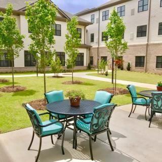 A landscaped courtyard with outdoor seating and a modern apartment building backdrop.