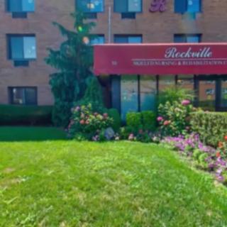 A residential building with a well-maintained garden and a red awning above the entrance.
