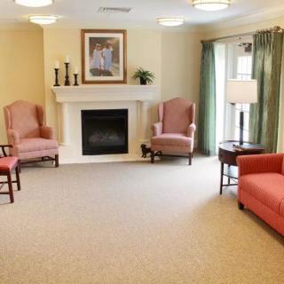 A cozy living room with a fireplace, comfortable chairs, and a sofa.