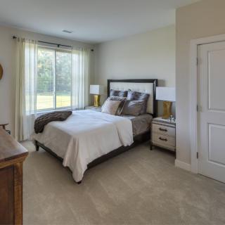 A cozy bedroom with a neatly made bed, two nightstands, and a window letting in natural light.