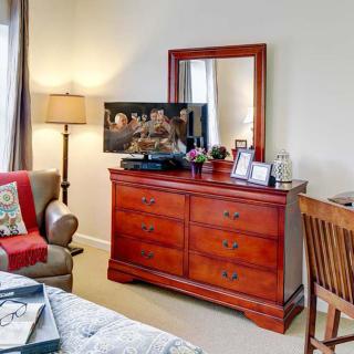 A cozy bedroom setup with a wooden dresser, mirror, and various decorative items.