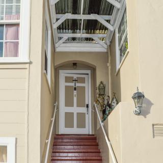 A front entrance with stairs leading to a door, covered by an awning, featuring exterior lamps.