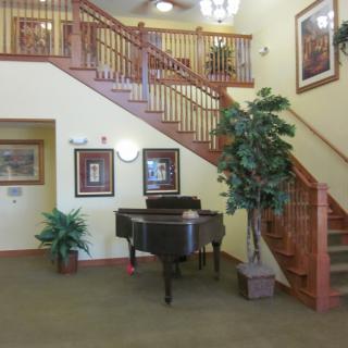A cozy interior space featuring a grand piano and a wooden staircase.