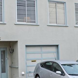 A residential house with a car parked in front of the garage.