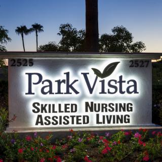 An illuminated sign for Park Vista Skilled Nursing and Assisted Living facility, set against an evening backdrop.