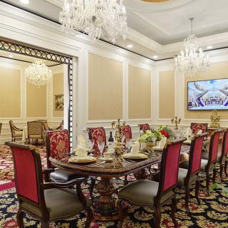 A luxurious dining room featuring elegant decor, a round table with red chairs, and chandeliers.