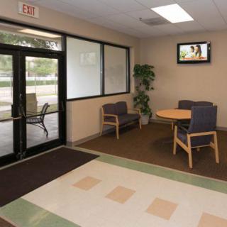 A small lobby area with chairs, a table, and a television near an entrance.