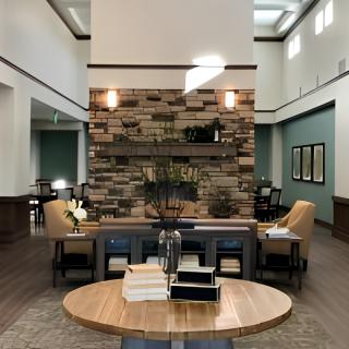 A modern lobby with stylish furniture and wood accents, featuring a central round table and comfortable seating.