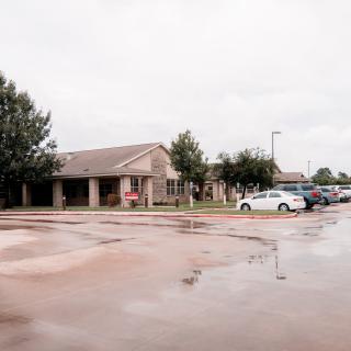 A suburban building with a parking lot on a cloudy day.