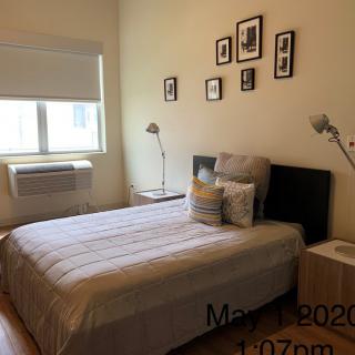 A neatly decorated bedroom with a bed, bedside tables, lamps, and framed pictures on the wall.