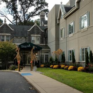 A building entrance with autumn decorations and well-maintained landscaping.