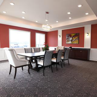 A modern dining room featuring elegant furniture, red accent walls, and chandelier lighting.