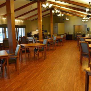 A spacious dining area with wooden tables and chairs, featuring warm lighting and a welcoming atmosphere.