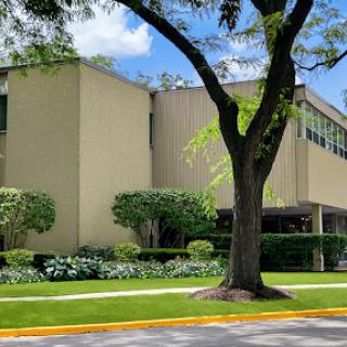 A modern building surrounded by greenery and flowers on a sunny day.