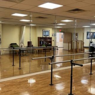 An empty dance studio with mirrors and ballet barres.