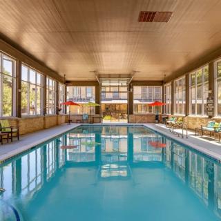 A tranquil indoor swimming pool with ample natural light filtering through large windows.